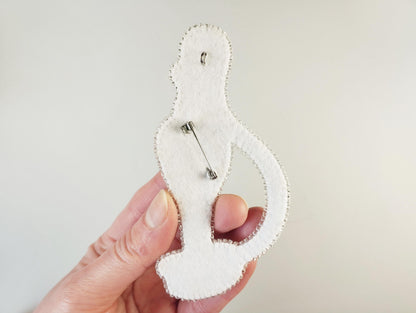 A hand holding a white felt object with a pin hole design on it.