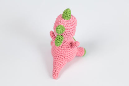 a pink crocheted toy with a green leaf on top