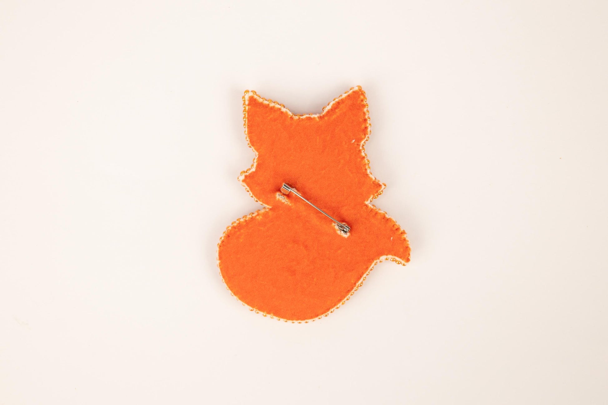 an orange brooch with a pin in the shape of a fox