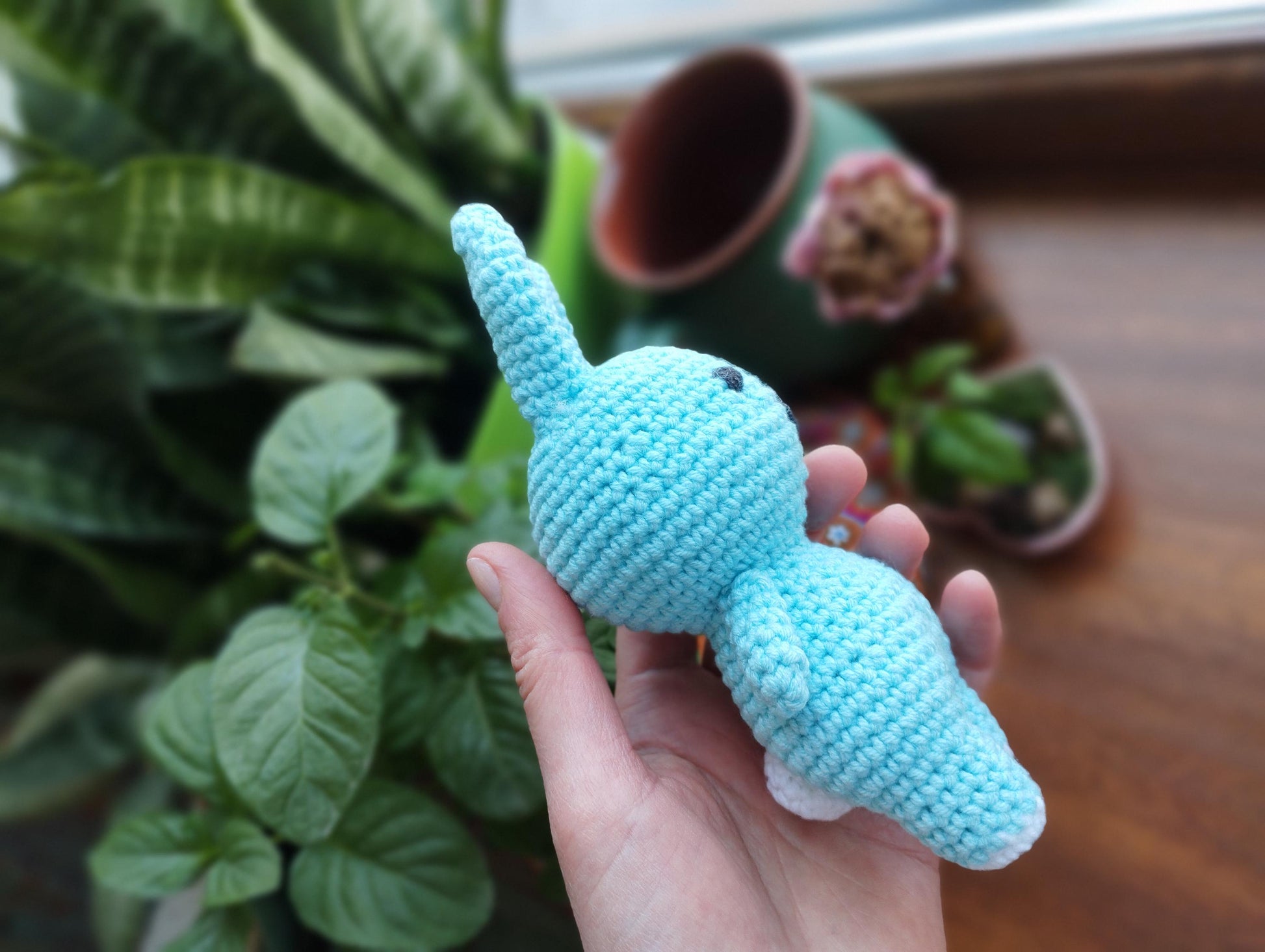 a hand holding a small crocheted blue elephant