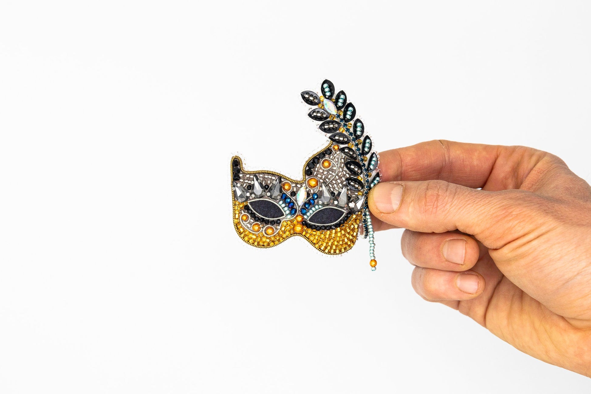 a hand holding a mask with a feather on it