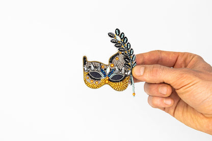 a hand holding a mask with a feather on it