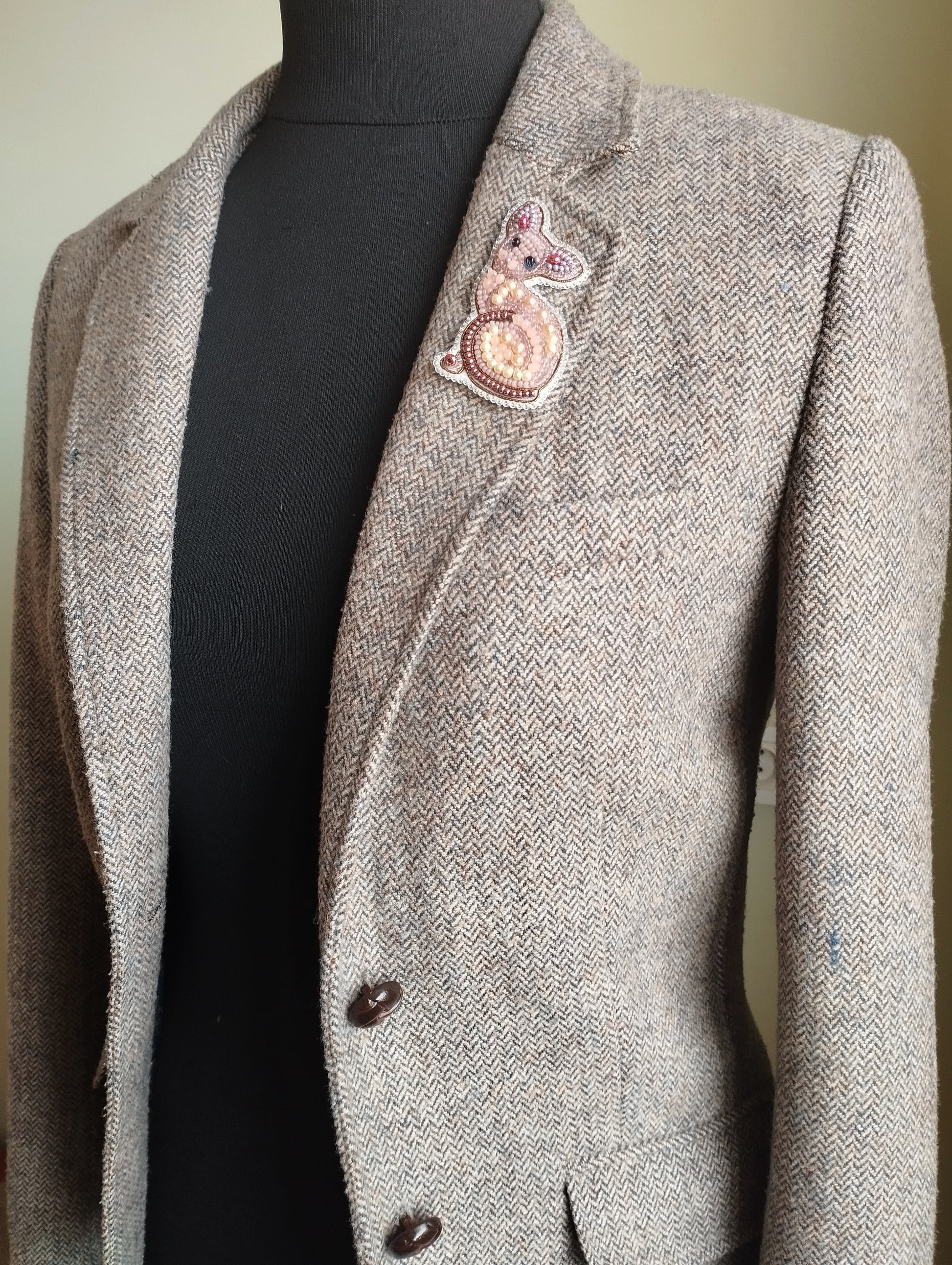 A gray tweed jacket with a small embroidered cat design on the left breast pocket area.