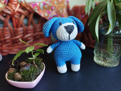 a crocheted teddy bear next to a potted plant