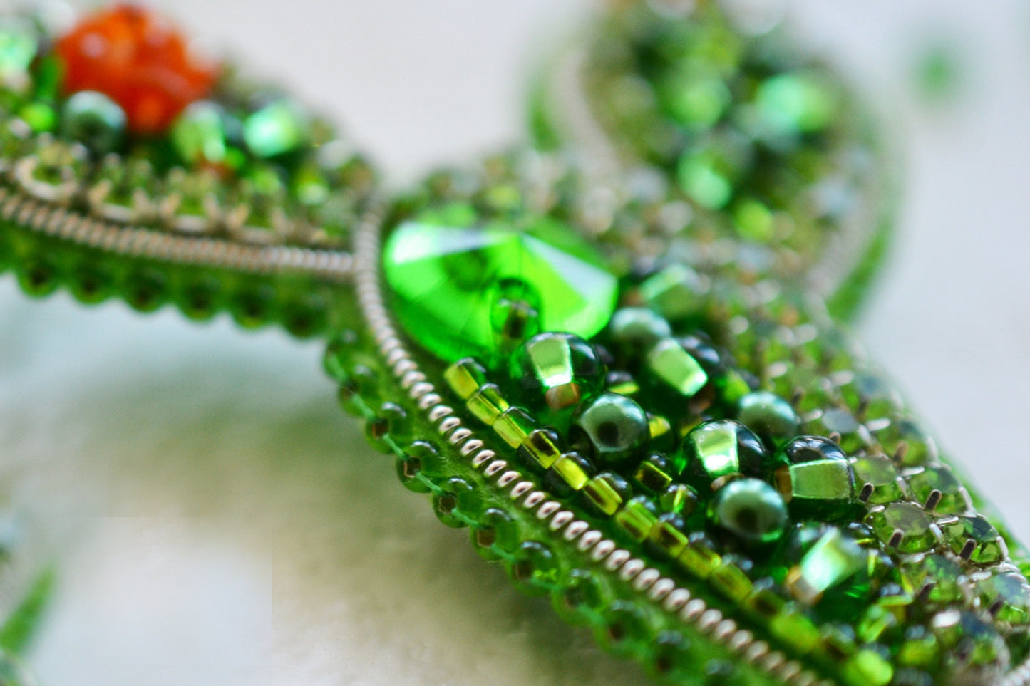 a close up of a green brooch with beads