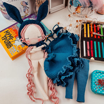 a crocheted doll laying on a table next to a box of croche