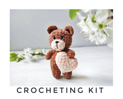 a crocheted teddy bear holding a heart