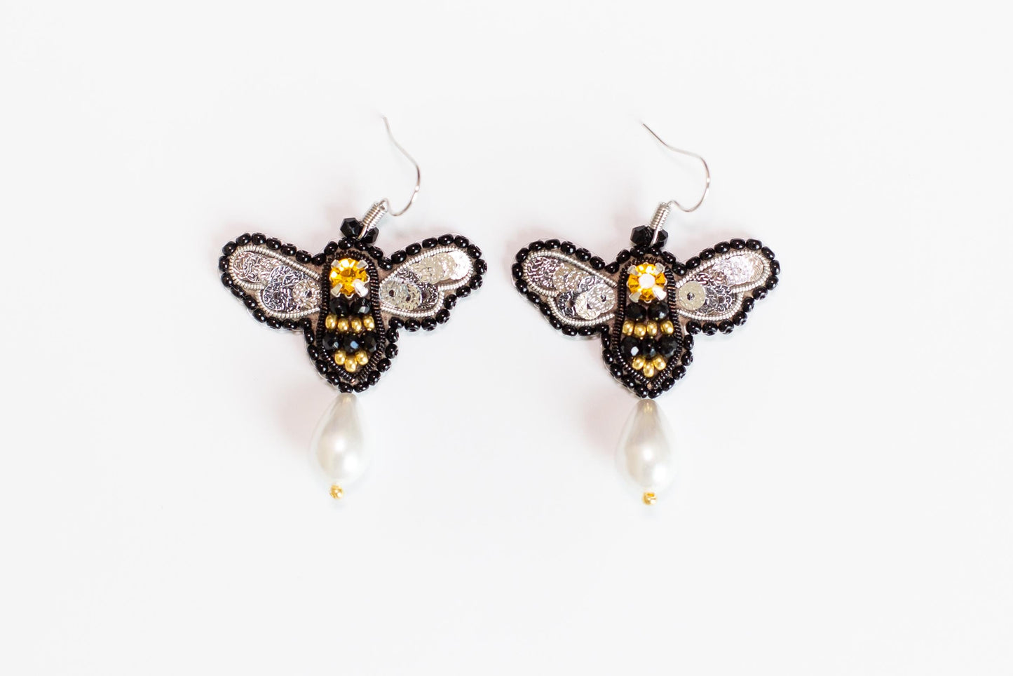 a pair of beaded bee earrings on a white background
