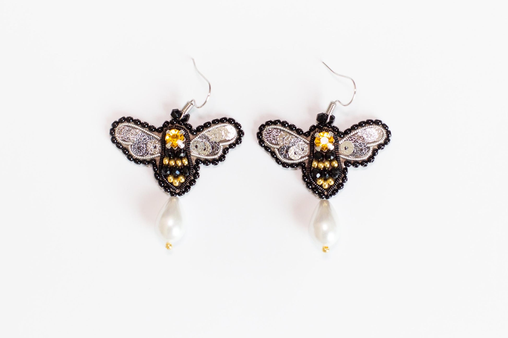 a pair of beaded bee earrings on a white background