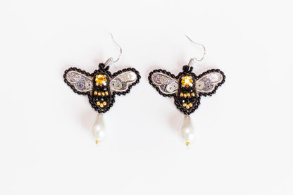 a pair of beaded bee earrings on a white background