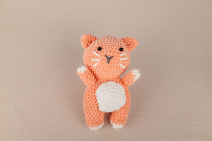 a small crocheted orange cat sitting on top of a table