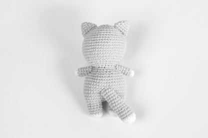 a crocheted teddy bear laying on a white surface