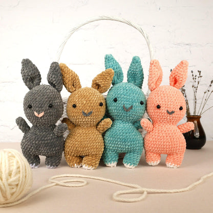 a group of crocheted rabbits sitting next to a ball of yarn