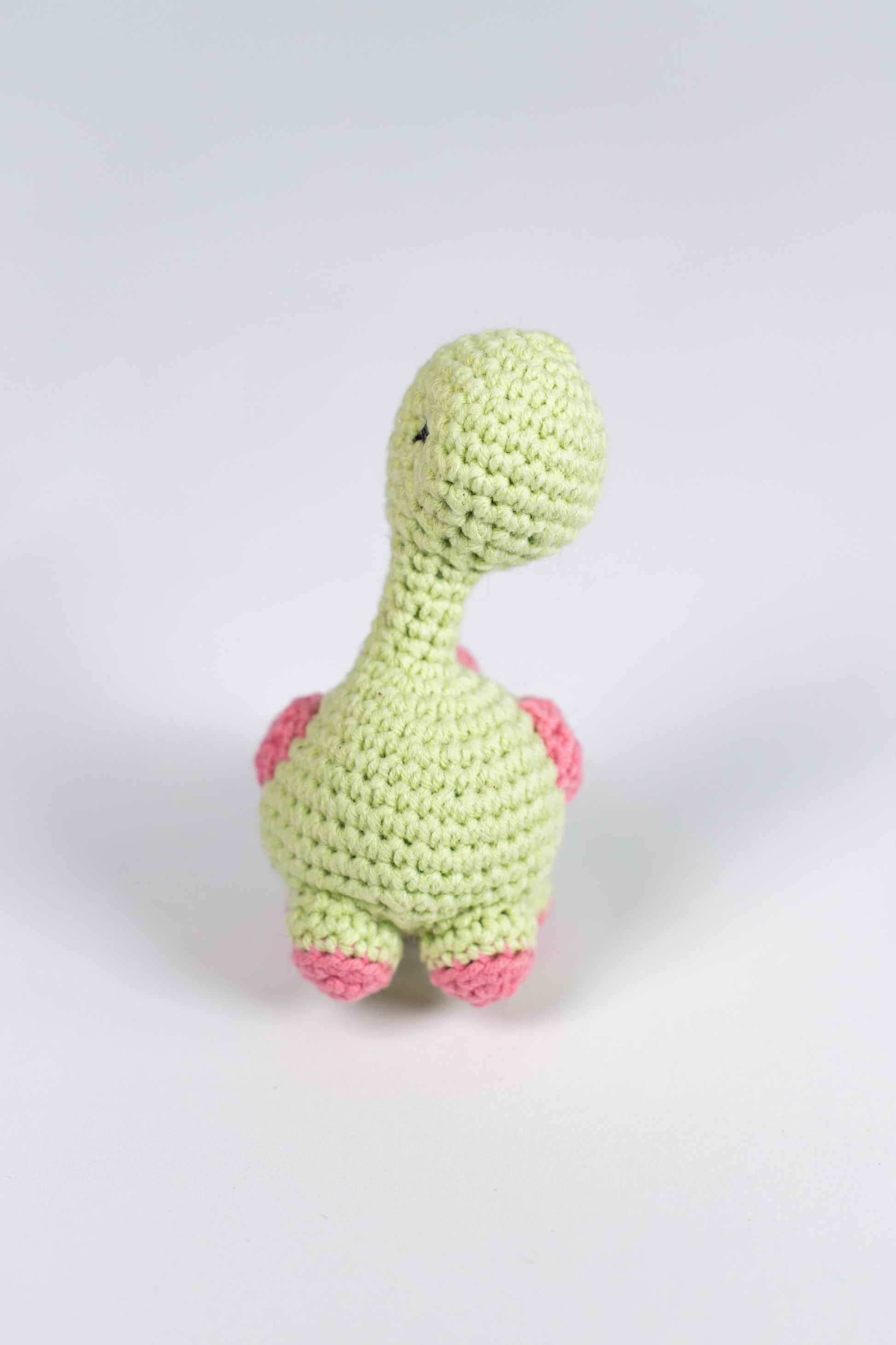 a crocheted toy of a green dinosaur