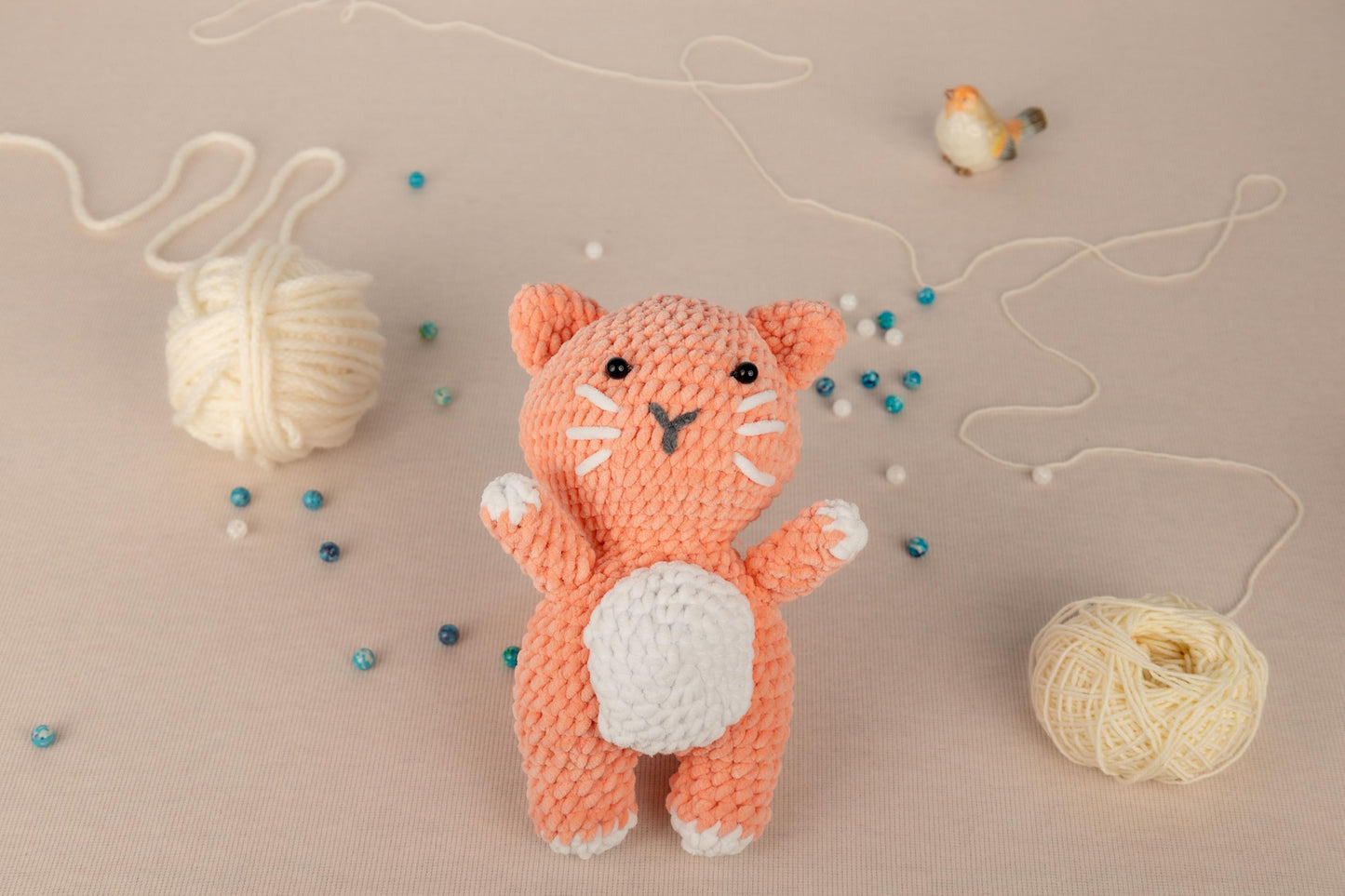 a crocheted cat standing next to a ball of yarn