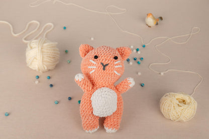 a crocheted cat standing next to a ball of yarn