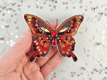 a hand is holding a colorful butterfly brooch