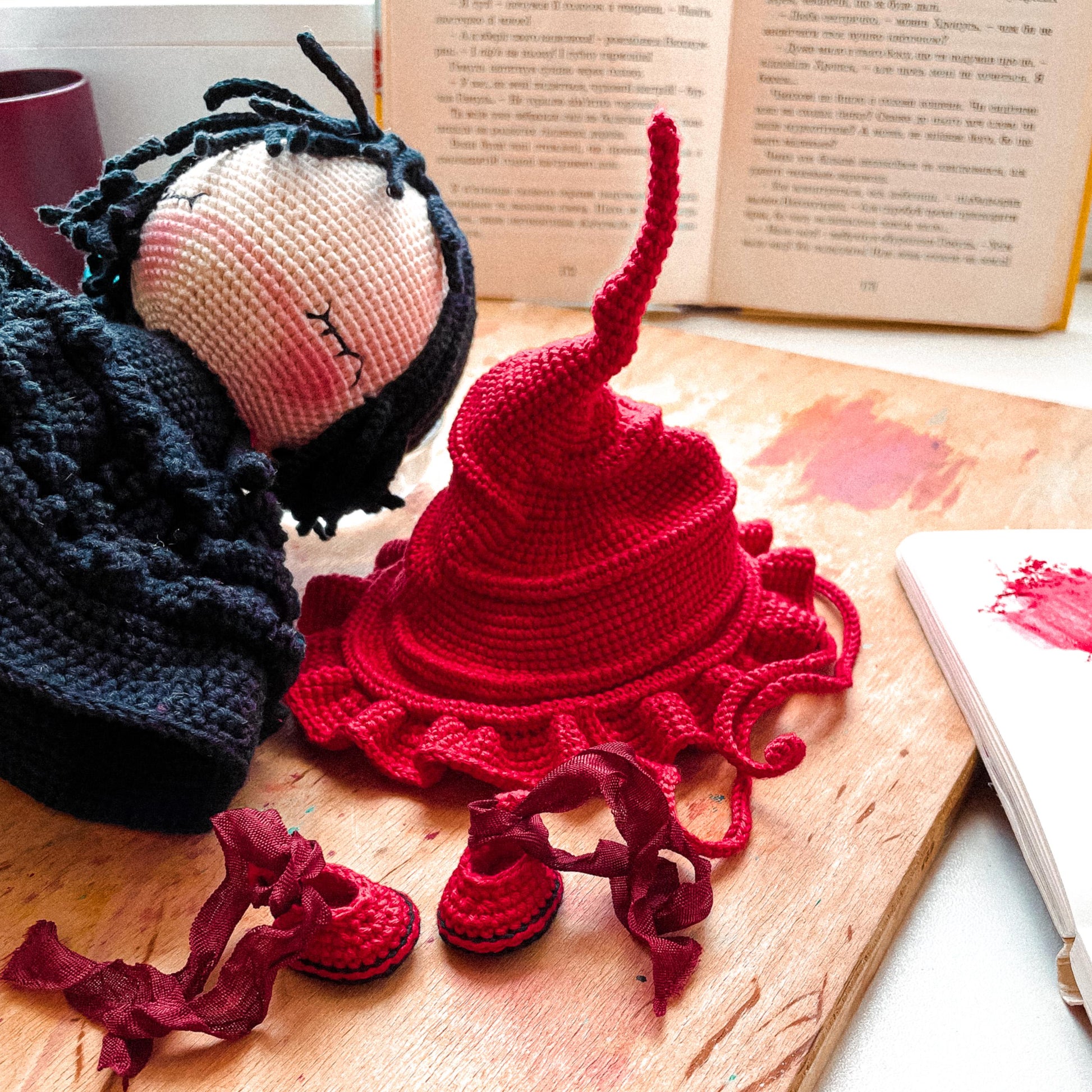 a knitted doll next to a knitted hat on a table