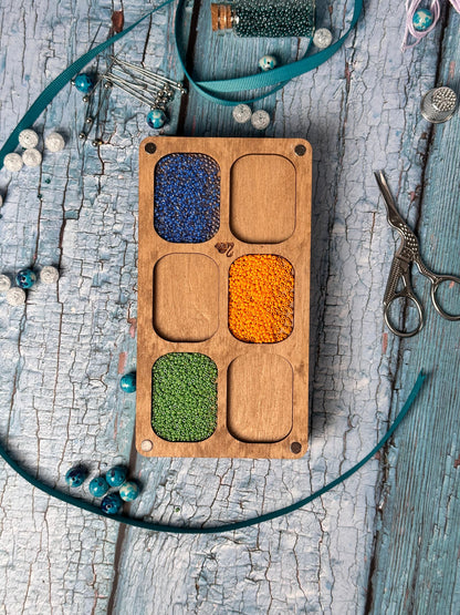 a wooden tray with beads and a pair of scissors