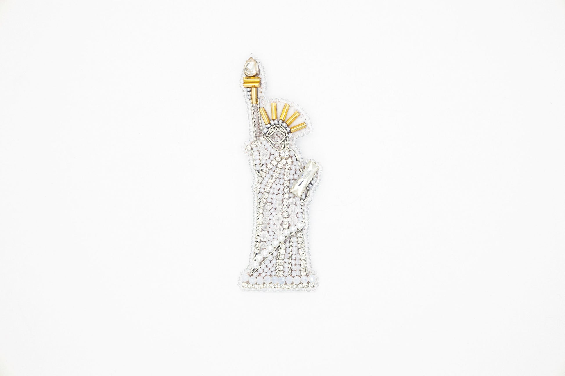 a white and gold brooch with a statue of liberty on it