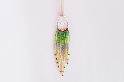 A beaded necklace with a large circular pendant featuring a gradient of green, purple, and yellow beads.