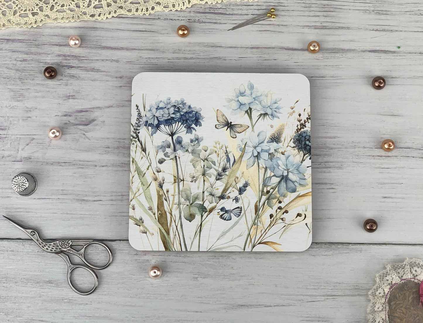 a coaster with a painting of flowers and a butterfly on it