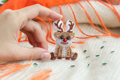 a hand is holding a beaded reindeer ornament