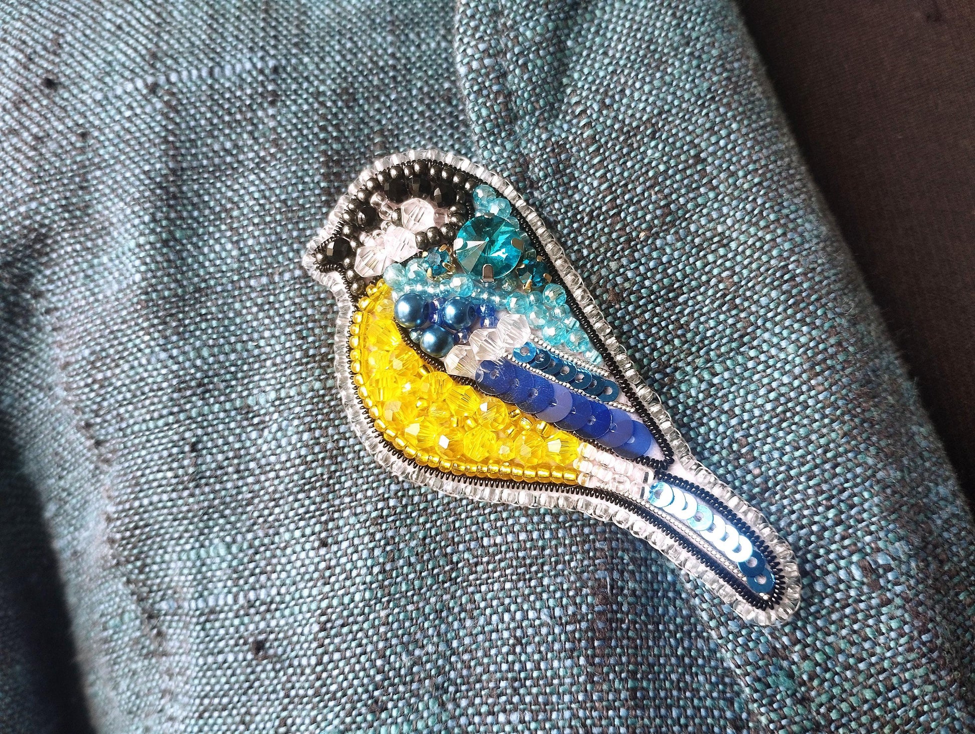 a blue and yellow bird sitting on top of a blue jacket