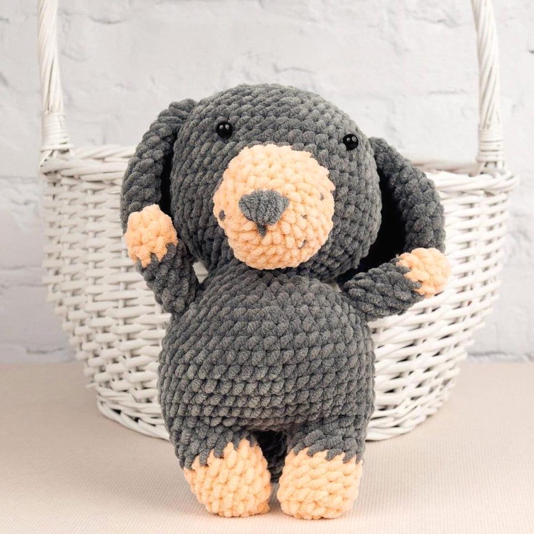 a crocheted teddy bear sitting on a table next to a ball of yarn