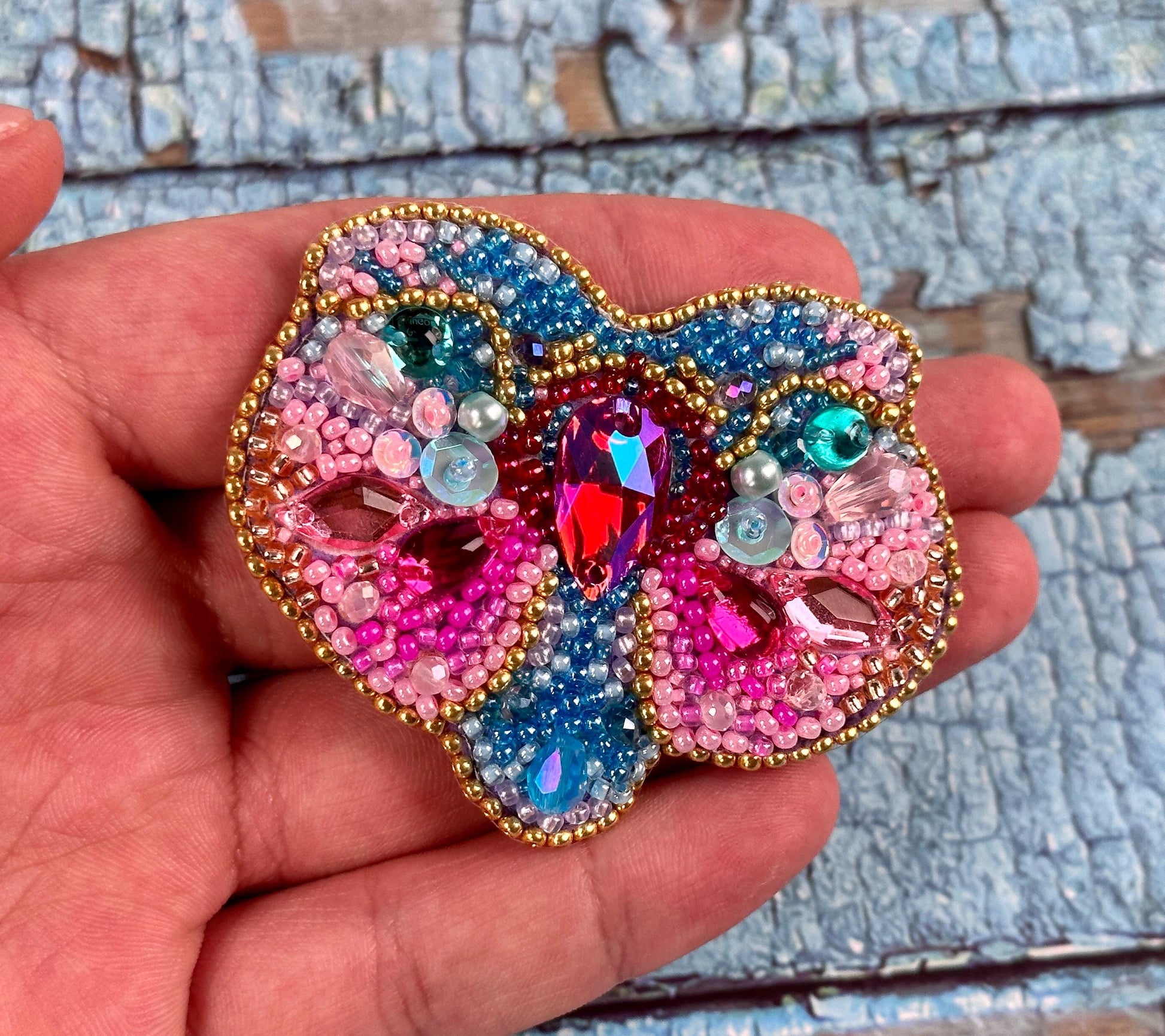 a person holding a colorful brooch in their hand