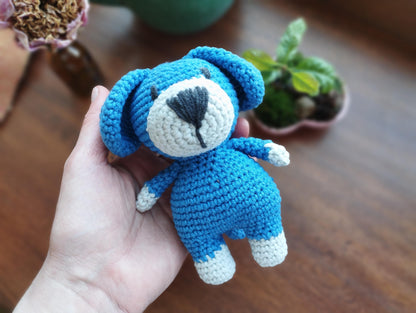 a hand holding a small crocheted blue teddy bear
