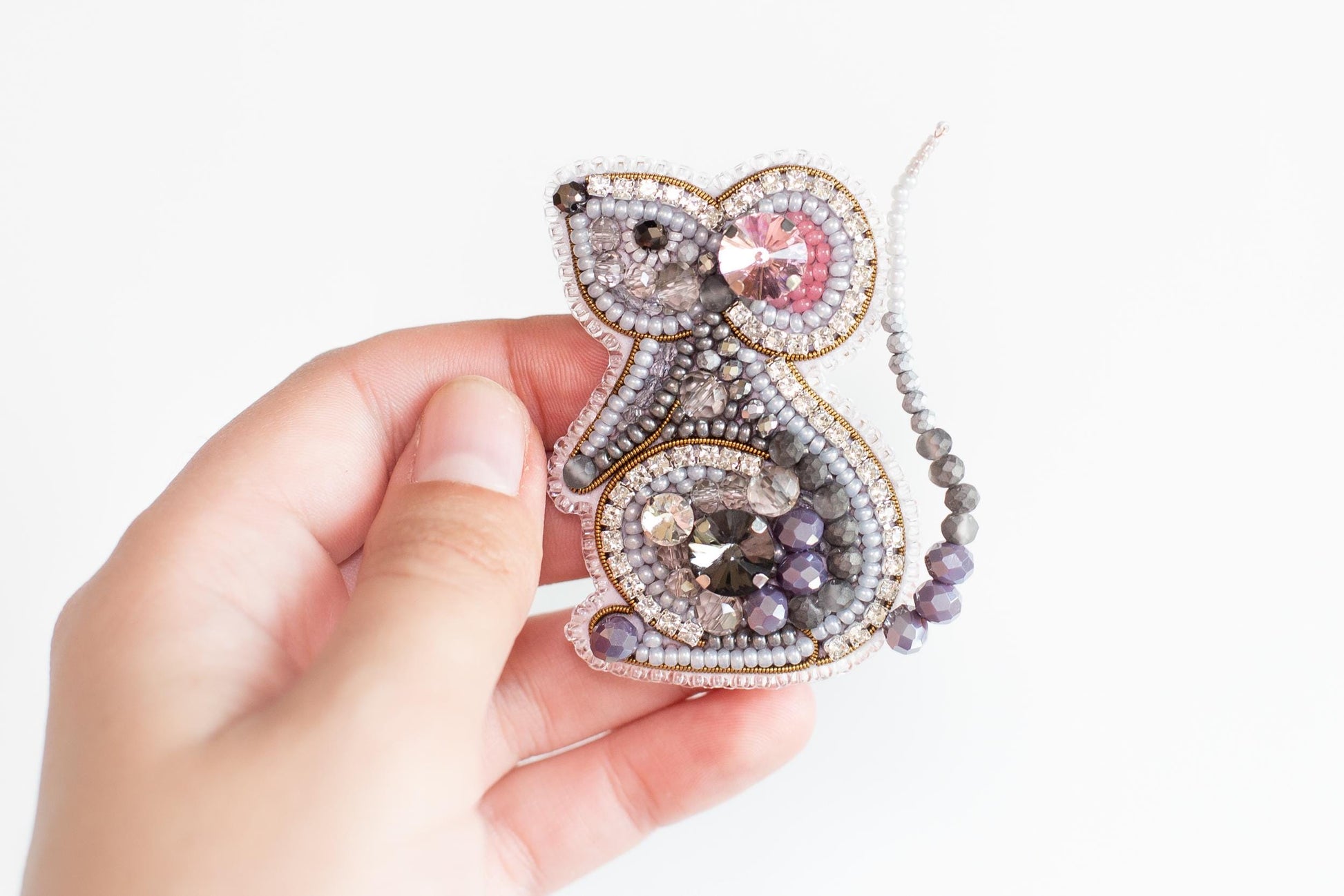 a person holding a beaded animal ornament in their hand