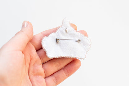 a person holding a small piece of cloth with a pin in it