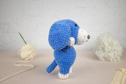 a crocheted blue dog standing next to a ball of yarn