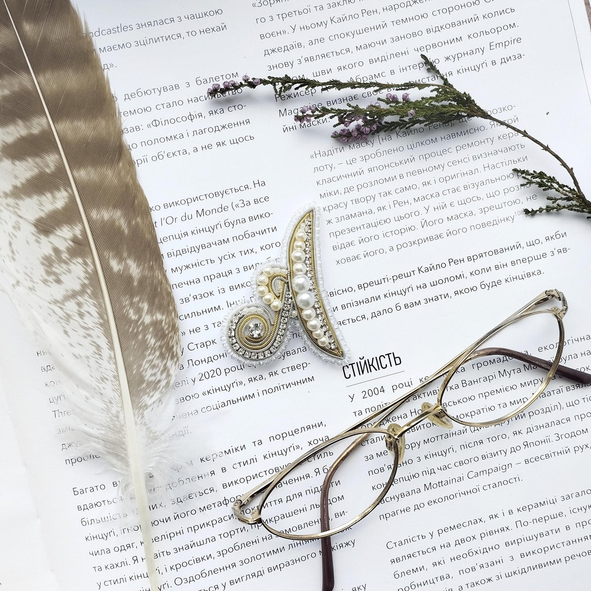 a close-up of a page with text in Russian, accompanied by a feather and a pair of glasses.