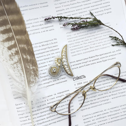 a close-up of a page with text in Russian, accompanied by a feather and a pair of glasses.