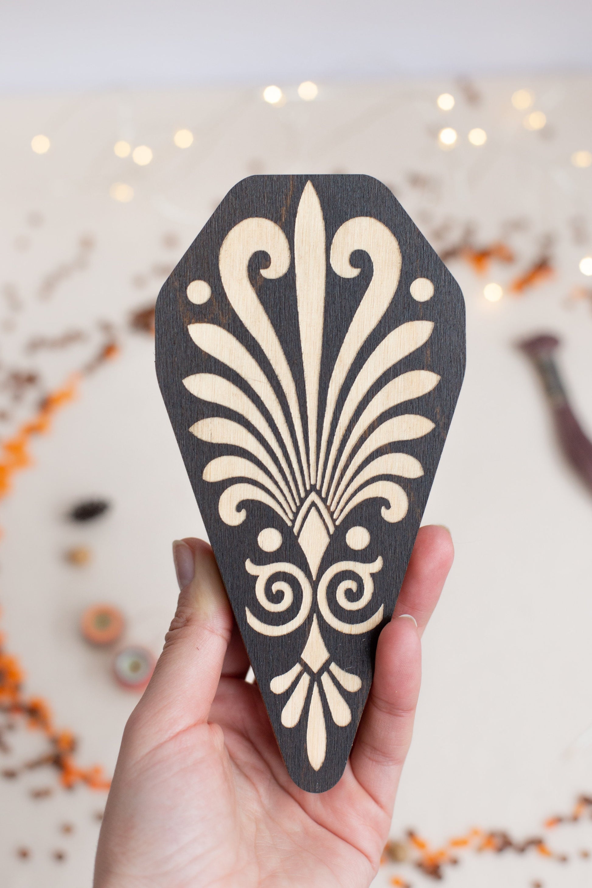 a hand holding a piece of wood with a design on it