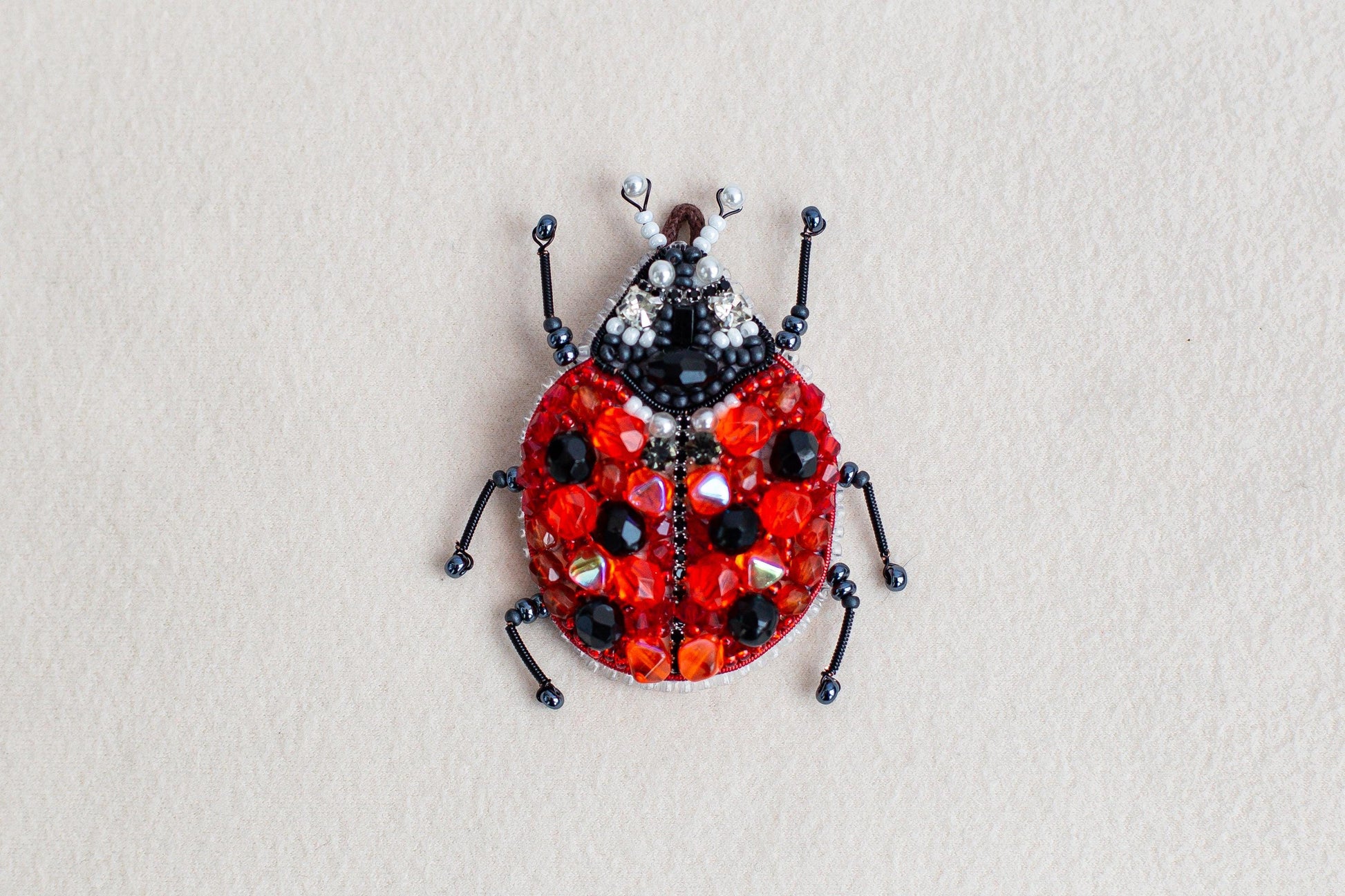 a beaded lady bug sitting on top of a white surface