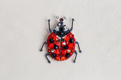 a beaded lady bug sitting on top of a white surface