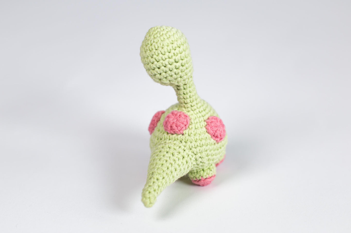 a crocheted stuffed animal with a pink flower on its head
