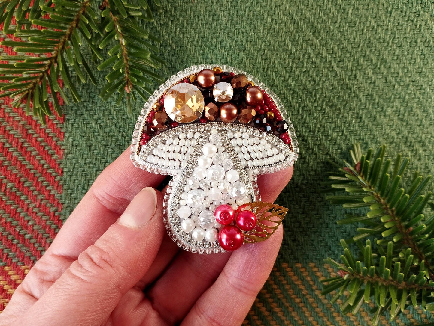 a hand is holding a brooch with beads on it