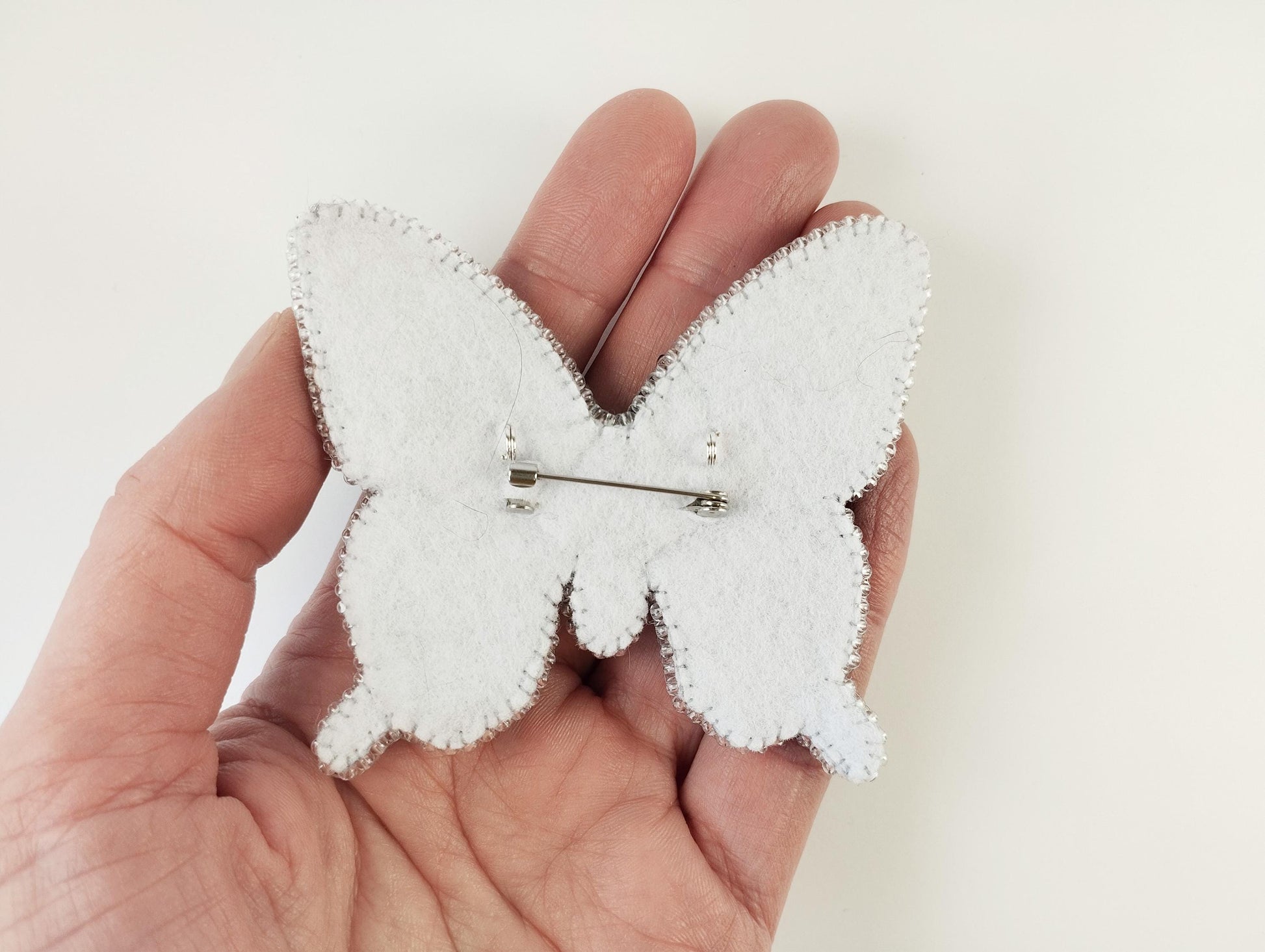 a person holding a small white butterfly brooch