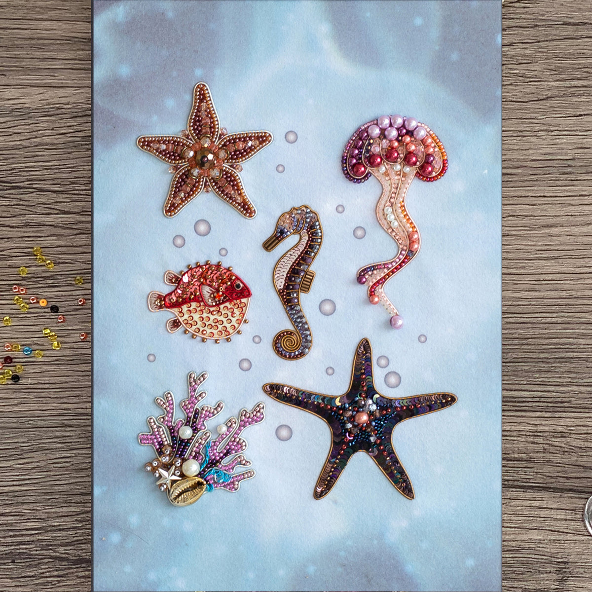 a collection of six decorative sea-themed items, including a starfish, a jellyfish, a seahorse, a pearlfish, a starfish, and a coral.