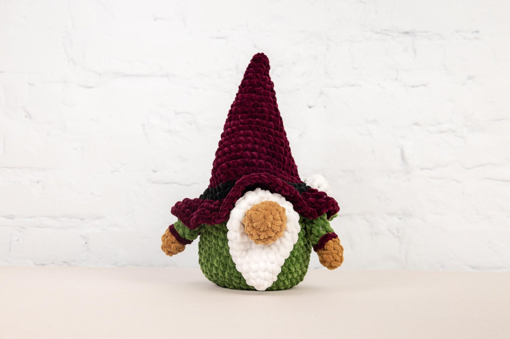 a crocheted gnome with a red hat and green pants