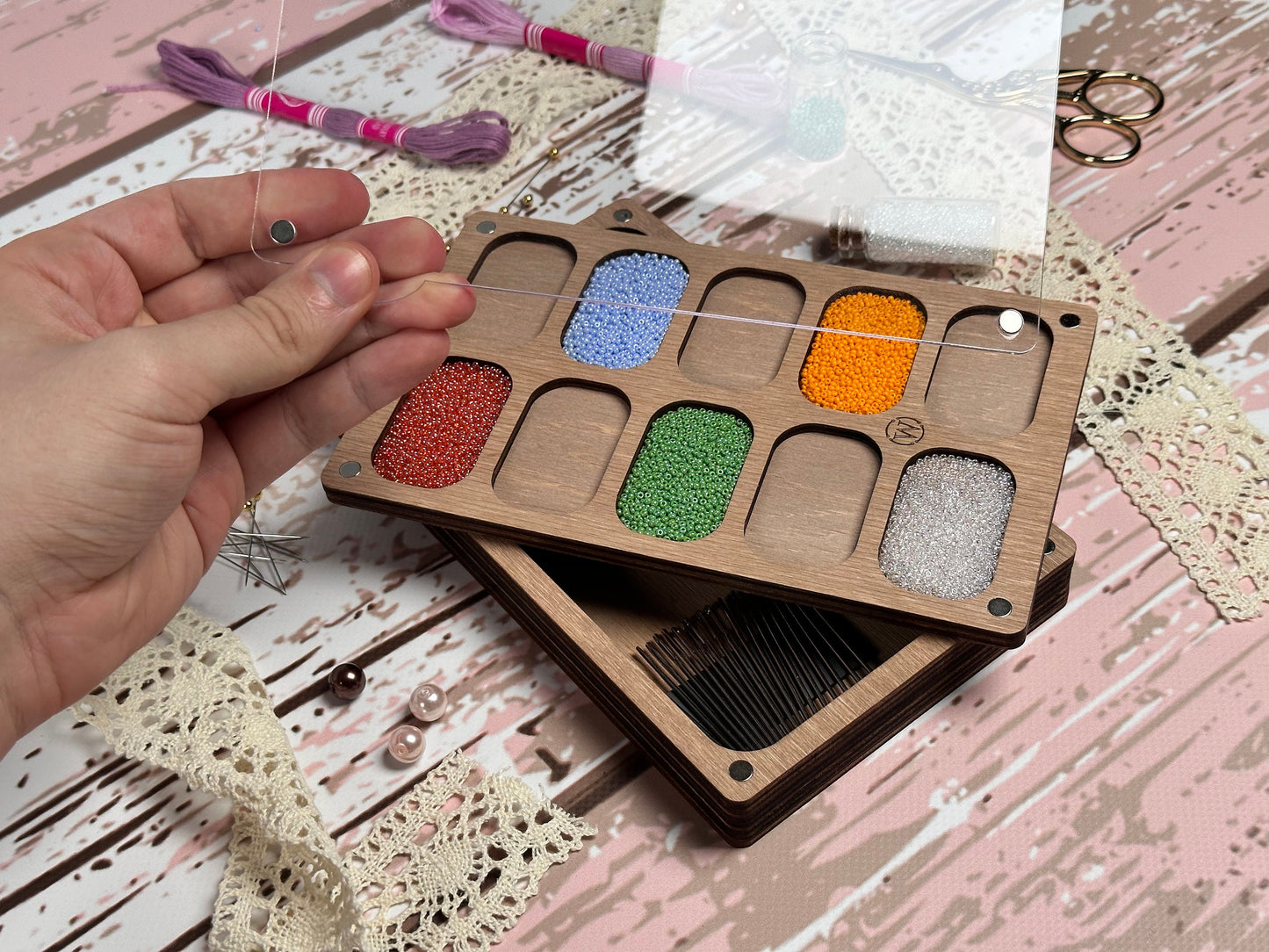 a person holding a wooden box with different colored beads in it