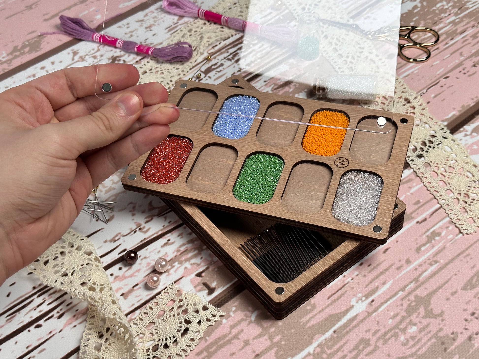 a person holding a wooden box with different colored beads in it