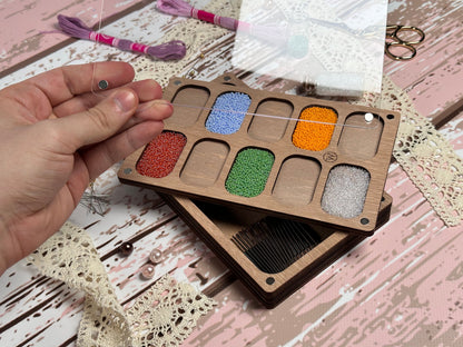 a person holding a wooden box with different colored beads in it