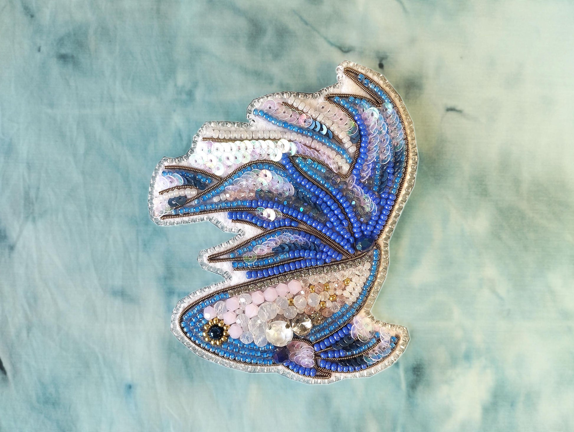 a decorative piece of embroidered or beaded art, with a blue and white color scheme.