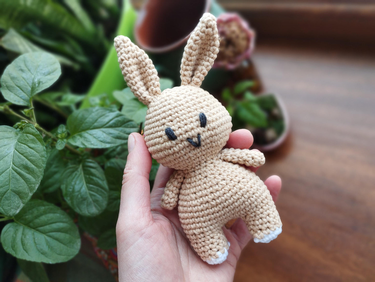 a crocheted bunny standing next to a vase of flowers