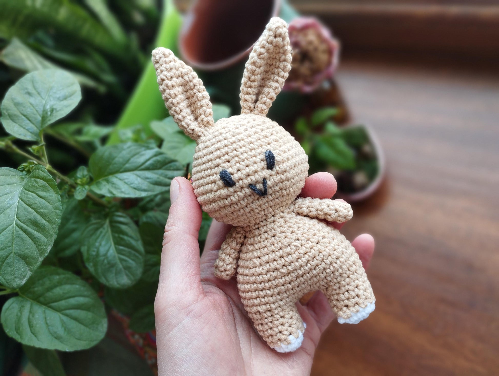 a crocheted bunny standing next to a vase of flowers